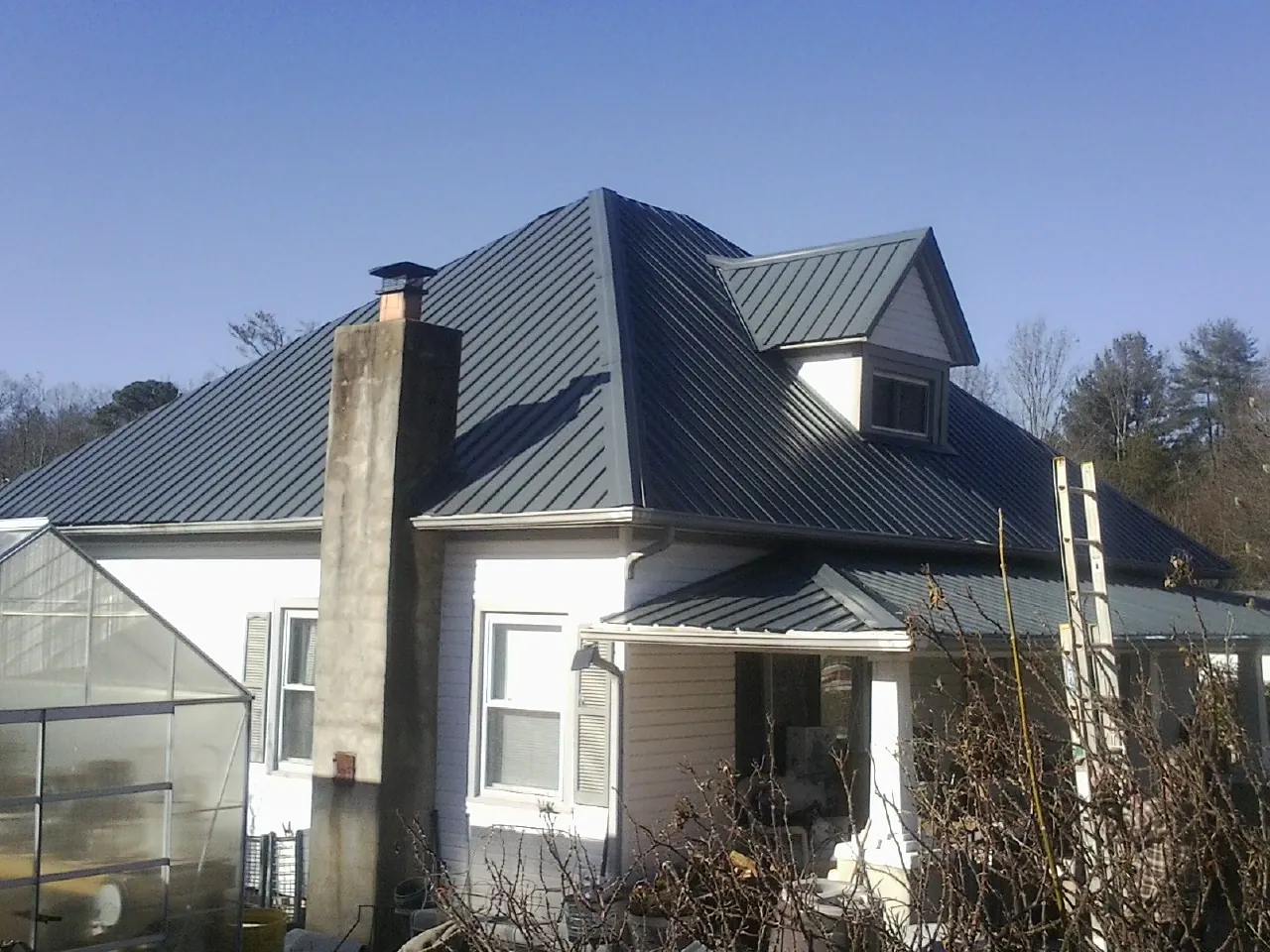 Dark blue standing seam metal roof on a white farmhouse with dormer — Slate & Tile Roof Repair by Roofing Brothers in Waymart