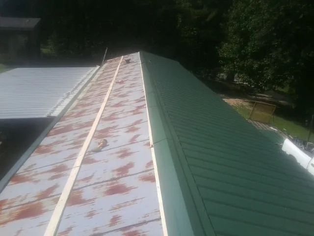 Old rusted panels beside newly installed green metal roofing — Wind Damage Roof Repair by Roofing Brothers in Waymart