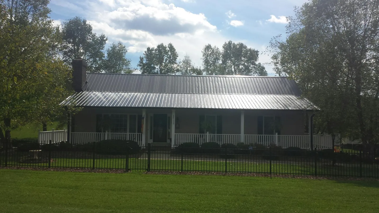 Gray metal roof on a brick ranch with a full width front porch — Gutter Guard Installation work by our crew in Waymart