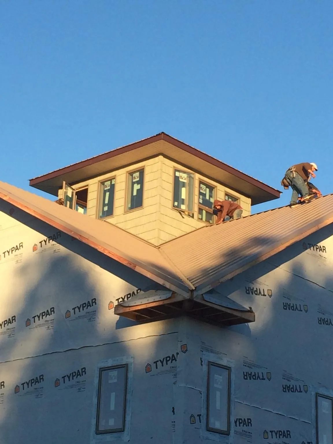 Roofers working around a rooftop cupola on a new metal roof at sunset — Roof Waterproofing in Waymart by Roofing Brothers